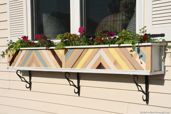 Plain white window planter box dressed up with painted scrap wood pieces in a chevron design