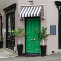 green front door with black and white awning on the society inc.