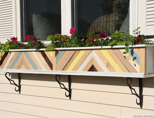 Plain white window planter box dressed up with painted scrap wood pieces in a chevron design