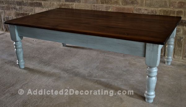 Finished coffee table makeover with stained pine wood top and antiqued blue painted base with turned legs