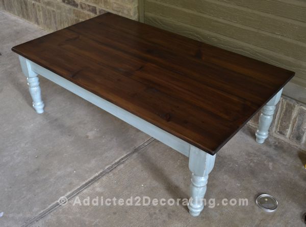 Finished coffee table makeover with stained pine wood top and antiqued blue painted base with turned legs