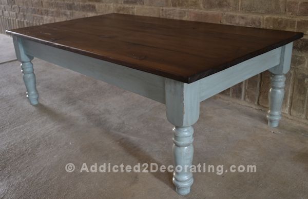 Finished coffee table makeover with stained pine wood top and antiqued blue painted base with turned legs