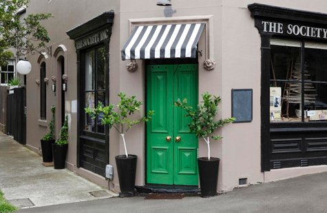 green front door with black and white awning on the society inc.