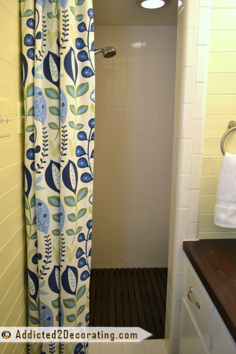 Shower makeover with cedar shower floor mat and colorful shower curtain - after