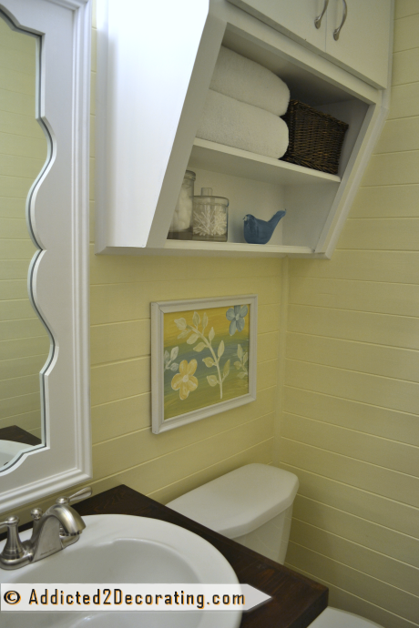 Dark wood wall cabinet in tiny bathroom painted white