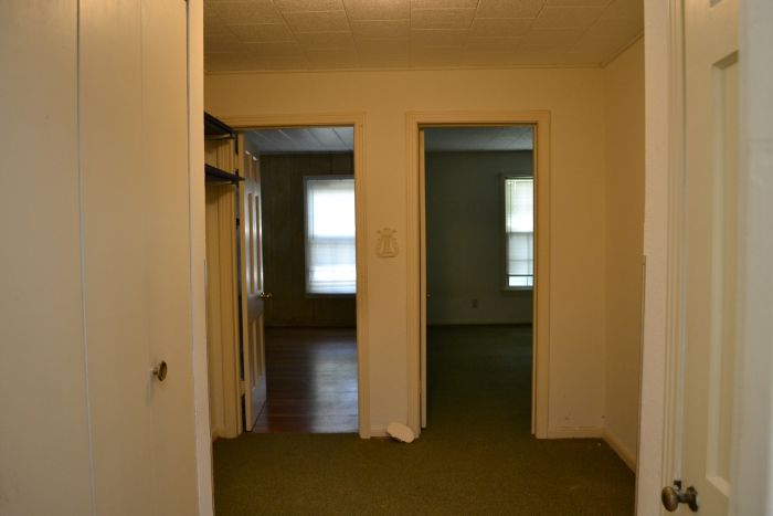 Hallway with original hardwood floors hidden under green carpet