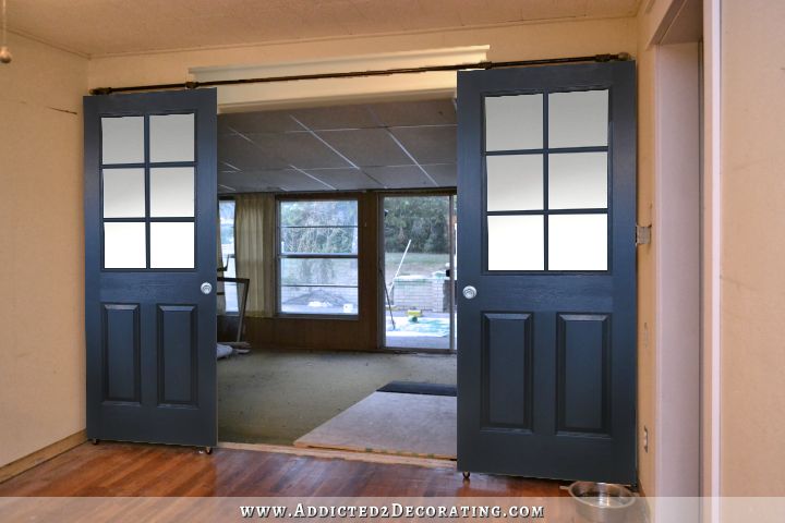 Black rolling barn door style doors with six panes of glass of equal size on top