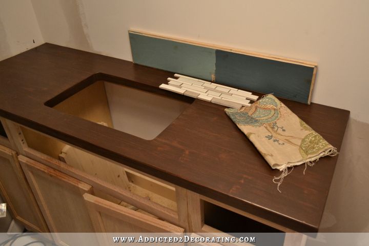 DIY butcherblock style countertop with coordinating paint colors, shower curtain fabric, and mosaic tile for backsplash