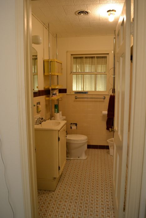 Outdated original bathroom from the late 1940s / early 1950s with mosaic tile floor and tiled walls and tub.