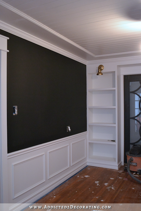 Black walls with white wainscoting and white bookcases
