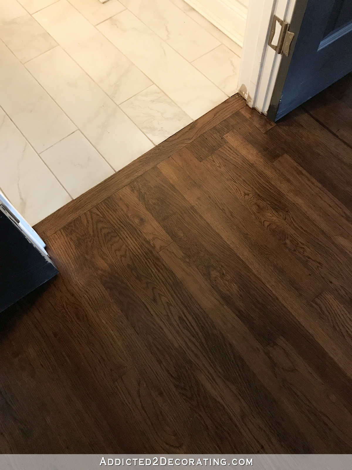 refinished red oak hardwood floors transition between hallway and tiled bathroom floor