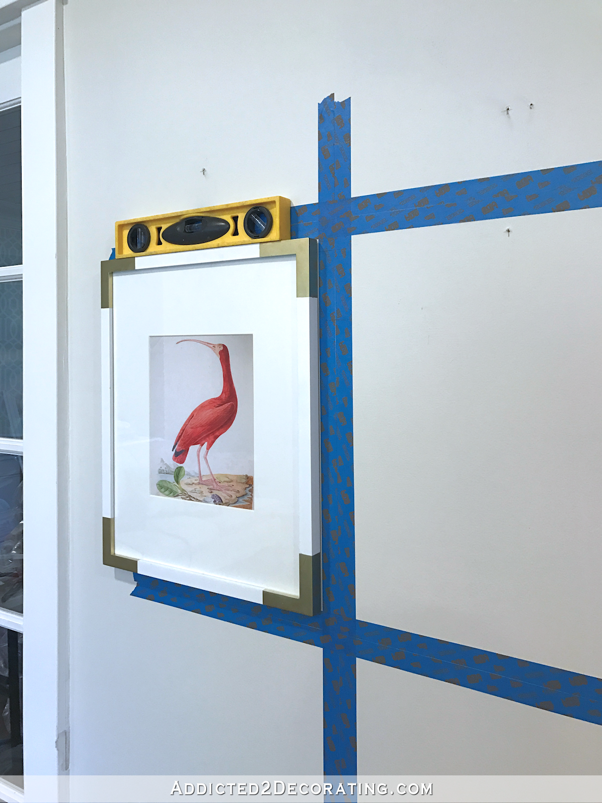 how to hang a perfect gallery wall - press frame to wall using taped grid and level for placement