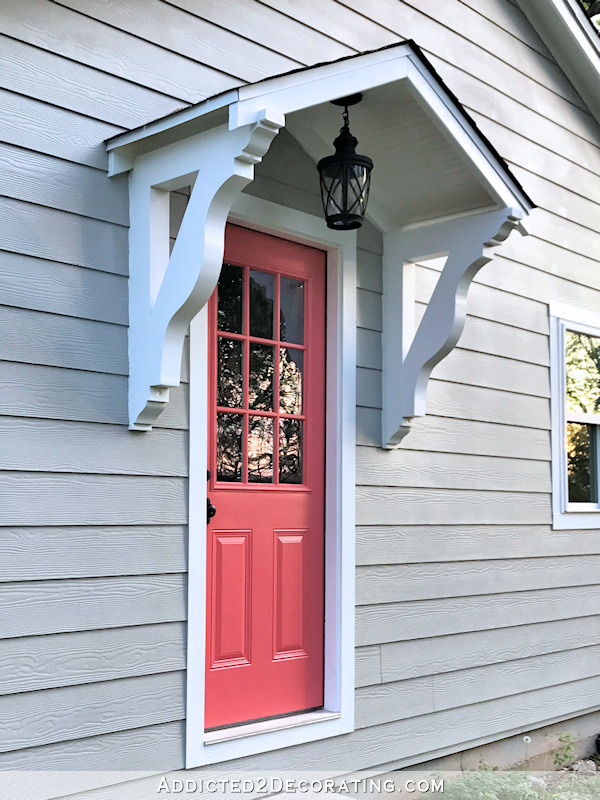 Portico with decorative corbels over a coral painted door