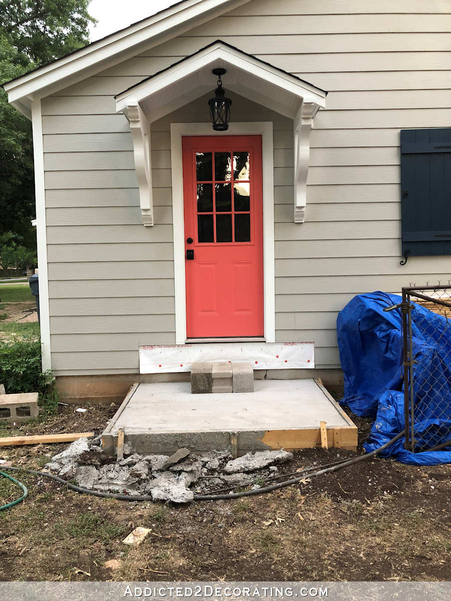 coral exterior door with small white portico on light gray siding, still need to build steps to the door