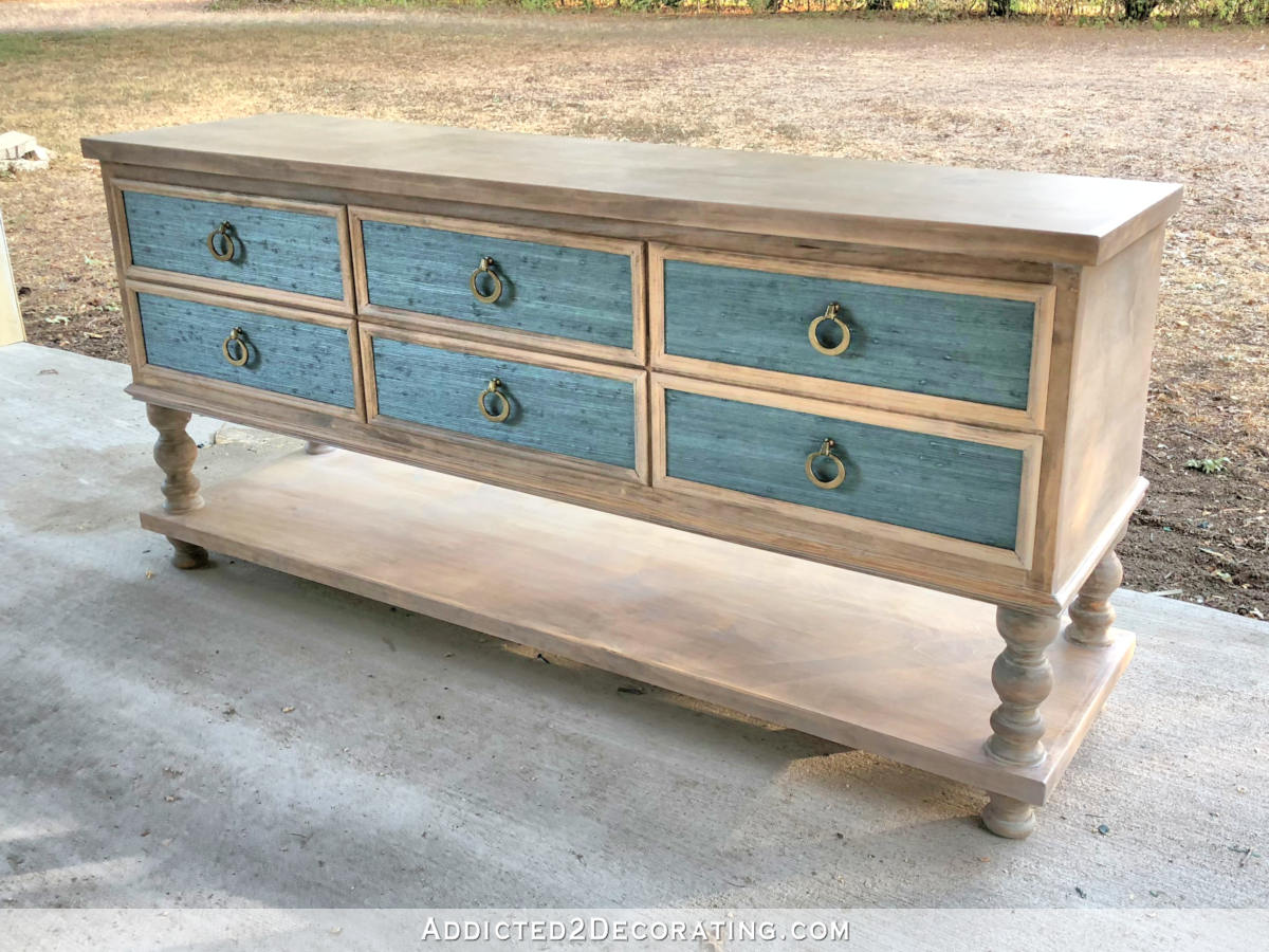 The finished DIY console table -- six drawers, grasscloth drawer fronts, open shelf below, turned legs