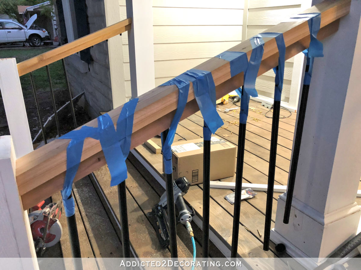 Attaching the balusters to the porch step railing frame - using tape for extra "hands".