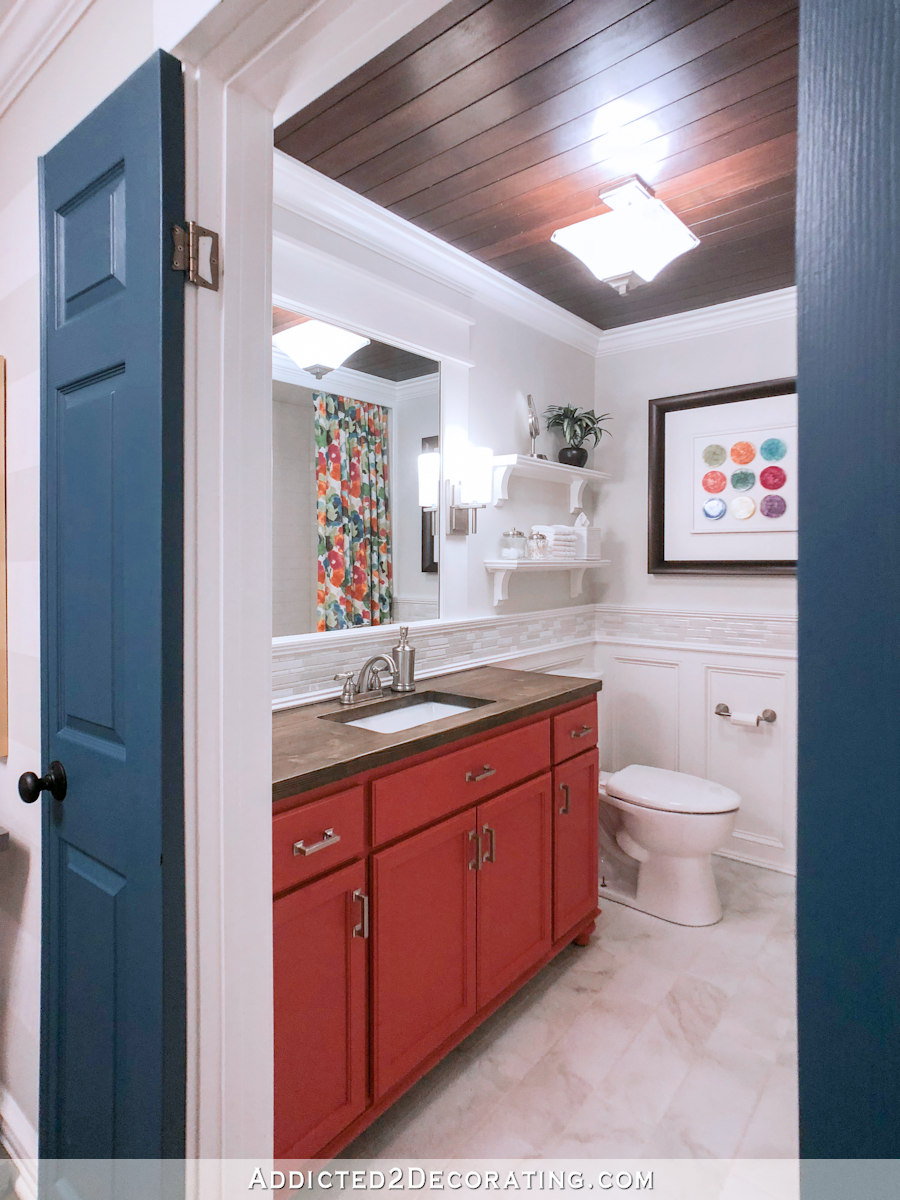 colorful small bathroom makeover with coral vanity, wood countertop and floral shower curtain