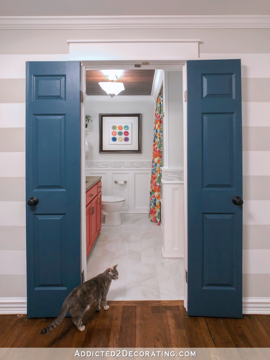 colorful hallway bathroom with horizontal stripe walls and dark teal interior doors