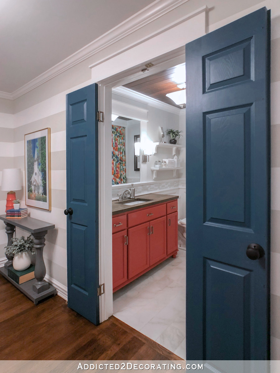 hallway bathroom with coral vanity and dark teal doors