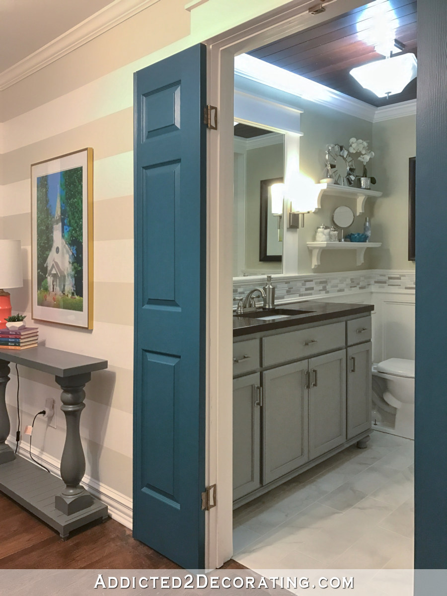 small hallway bathroom with dark teal doors and gray vanity