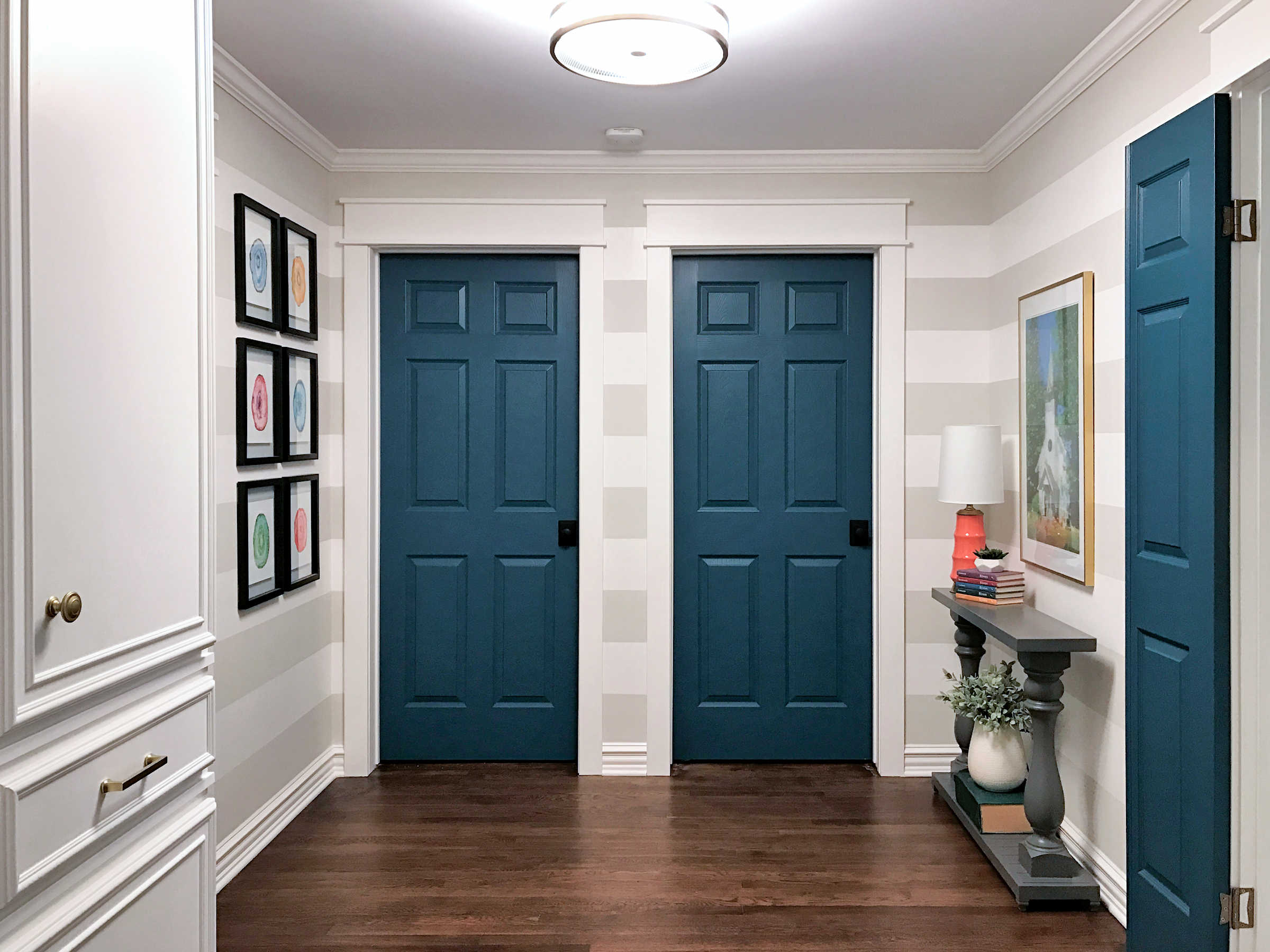 hallway remodel with striped walls, teal doors, and custom cabinet