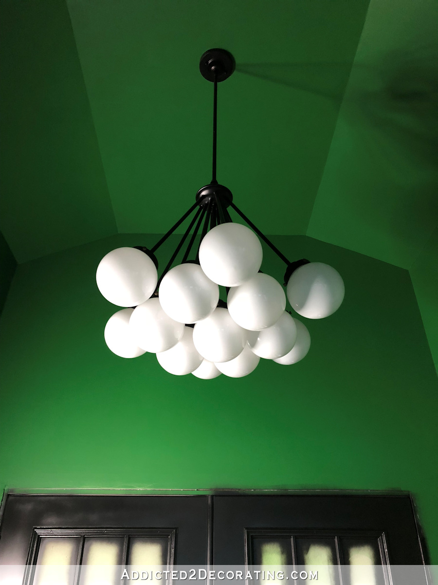 Black and white modern light fixture from Lowe's, in entryway with green walls and black French doors