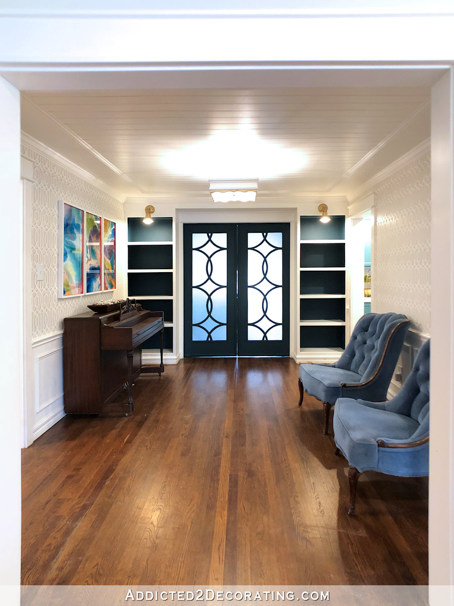current music room with backs of bookcases painted dark teal, dark teal doors, and white and gray walls