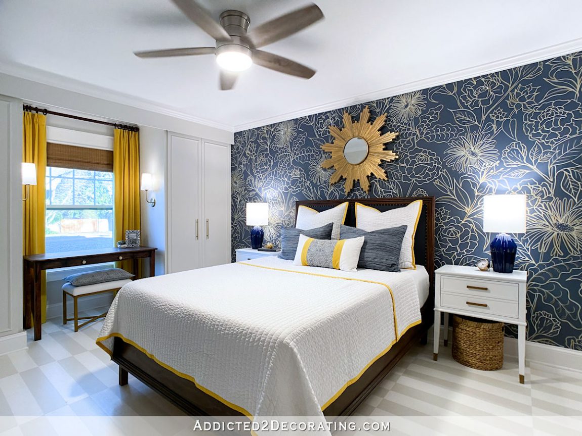 Guest bedroom with hand drawn floral wall design, upholstered headboard, painted hardwood floor, built in cabinet style closets