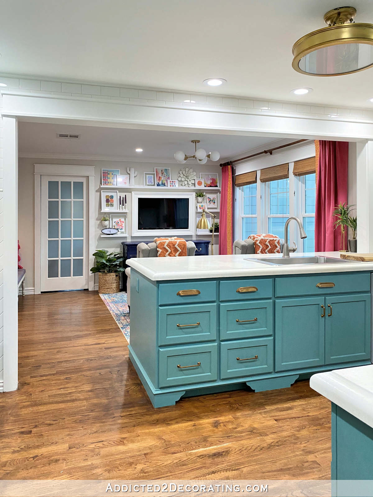 wide cased opening between kitchen and breakfast room (sitting room) - teal painted kitchen cabinets, picture ledge shelves with colorful artwork