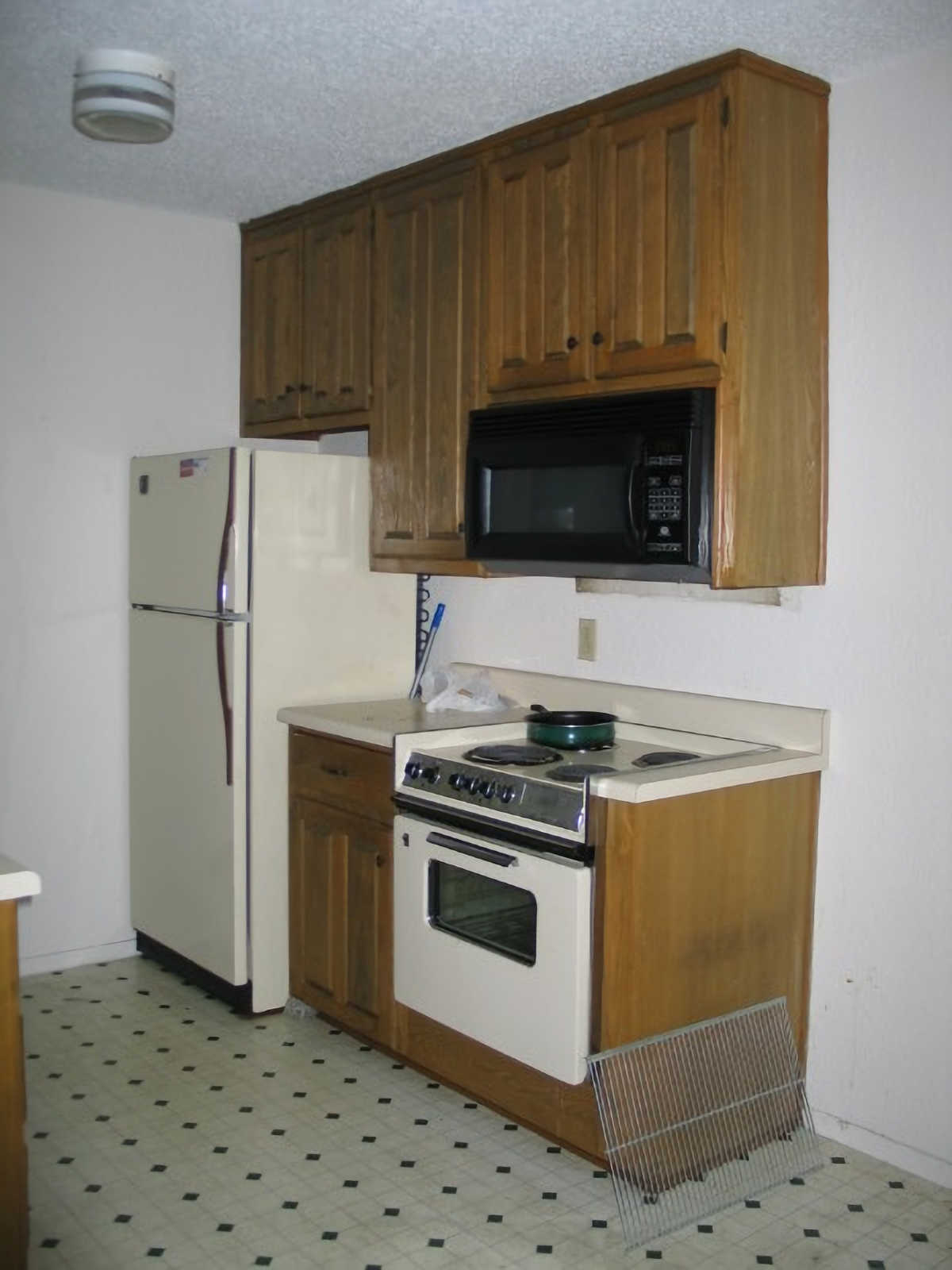 Original 1984 tiny condo kitchen with old appliances and stained wood cabinets