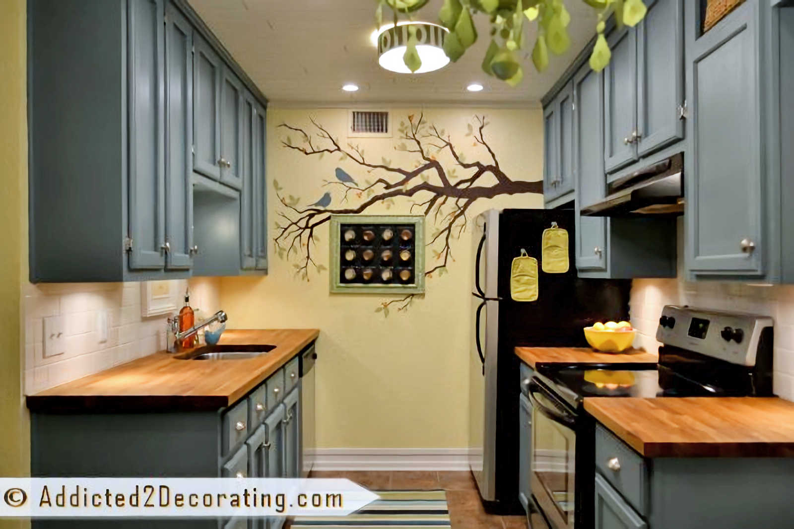condo kitchen remodel - after with teal cabinets, yellow walls, and painted tree mural