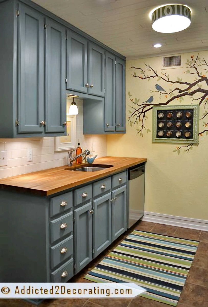 small condo kitchen design after remodel- teal cabinets, butcherblock countertop, white subway tile backsplash, yellow walls