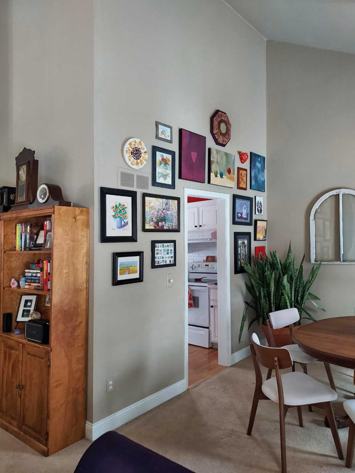 colorful gallery wall around doorway into kitchen on a wall with high vaulted ceiling