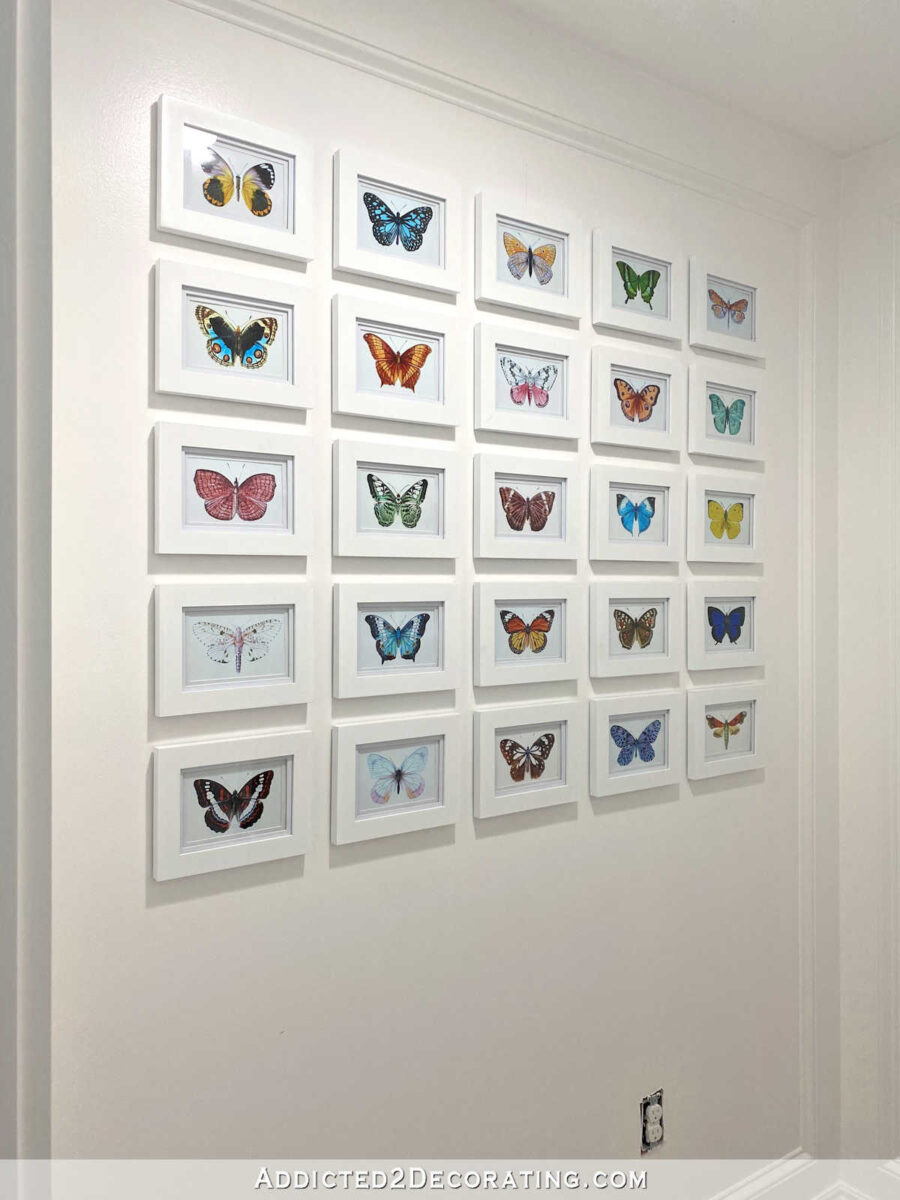 Gallery wall in master bathroom -- colorful butterflies in white frames on a white wall