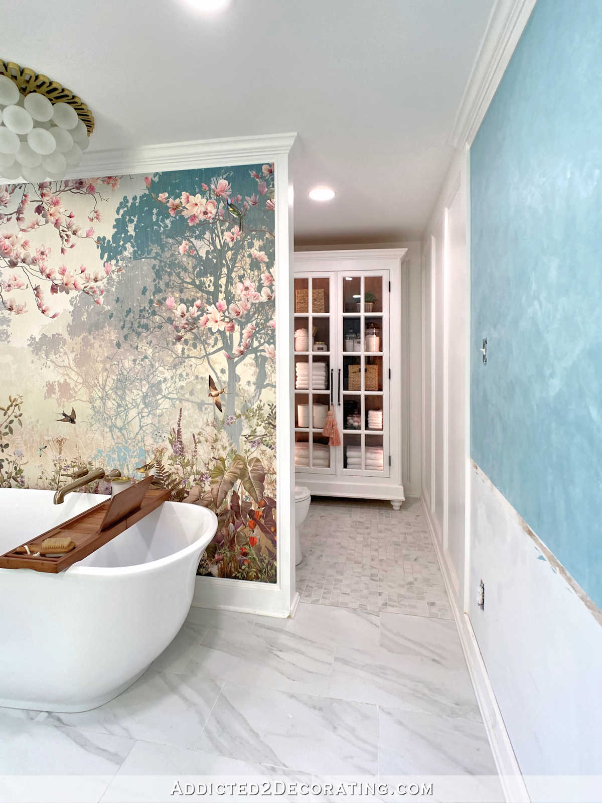 Master bathroom remodel in progress -- large forest mural behind standalone bathtub, water closet with large DIY curio cabinet