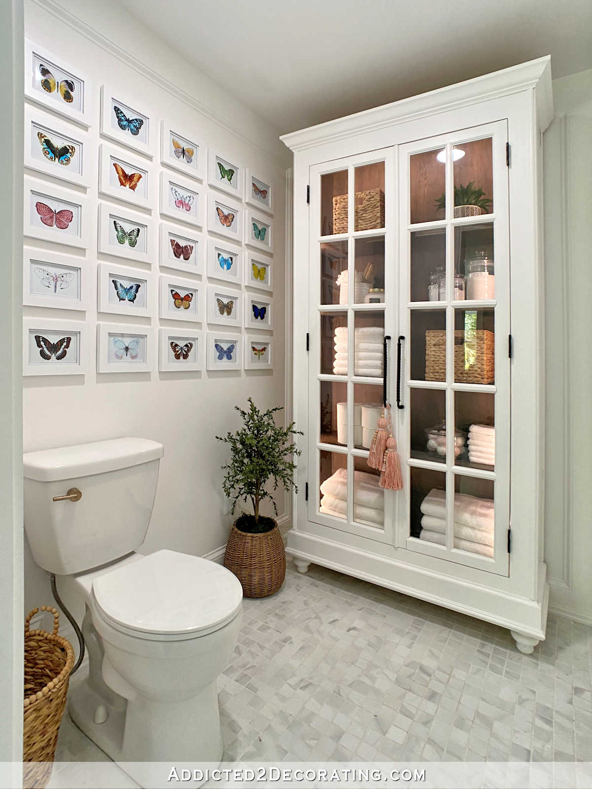 water closet area in master bathroom, large DIY storage cabinet with stained interior and painted exterior and French doors, grid gallery wall with butterfly illustrations
