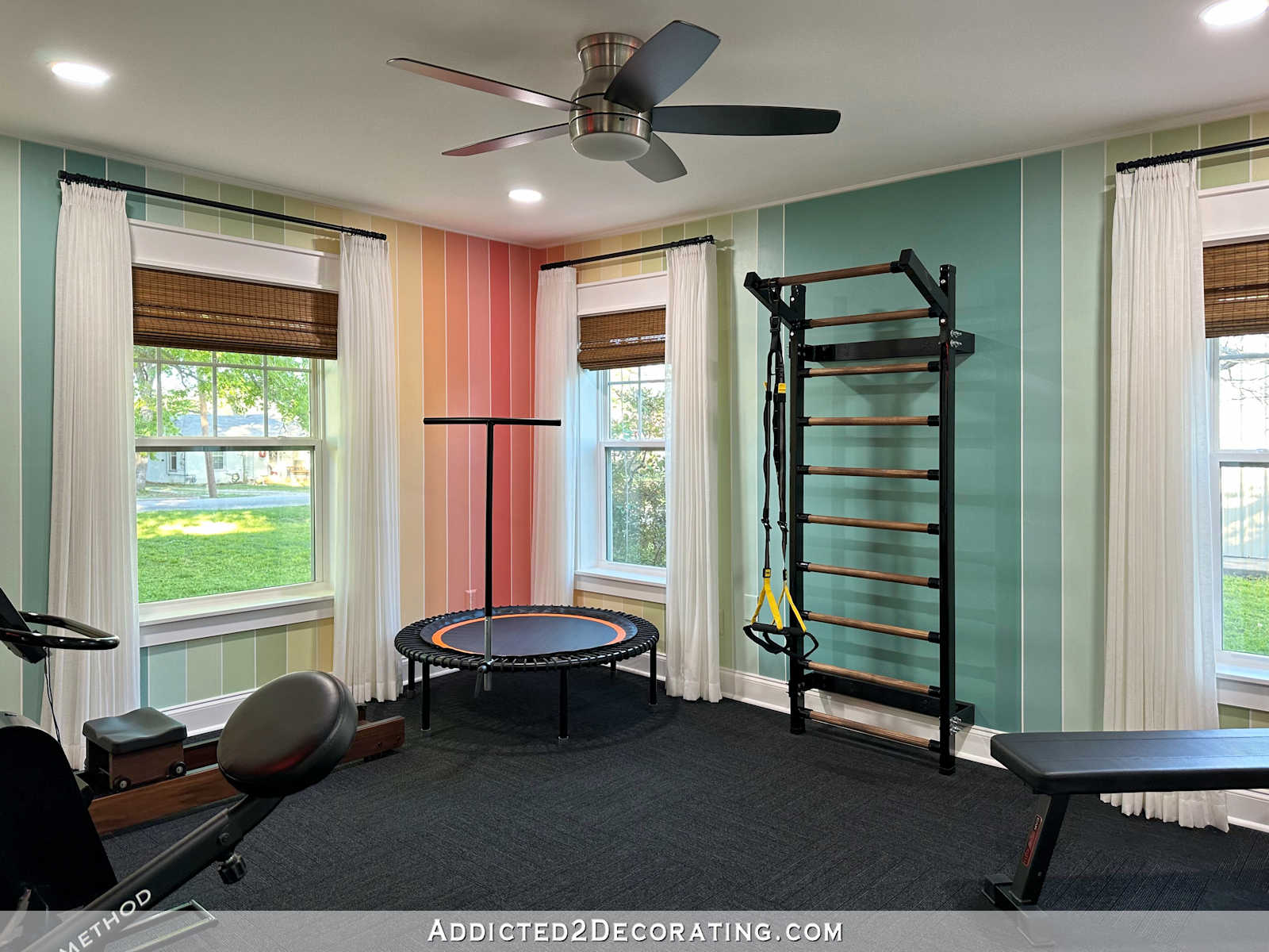 Home gym with colorful striped walls, white sheer curtains and FLOR carpet squares.