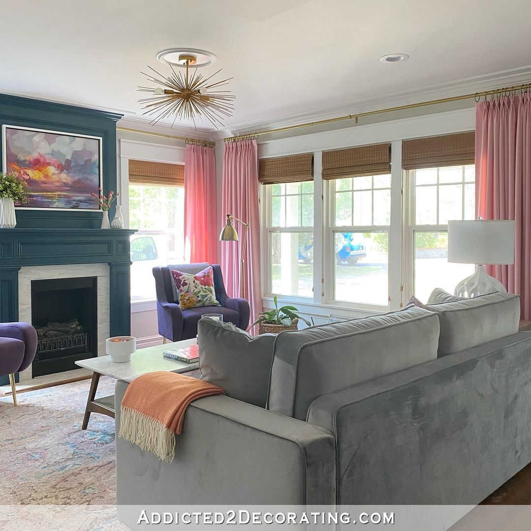 colorful living room with gray sofa, pink curtains, purple chairs, floral throw pillows, faux marble coffee table
