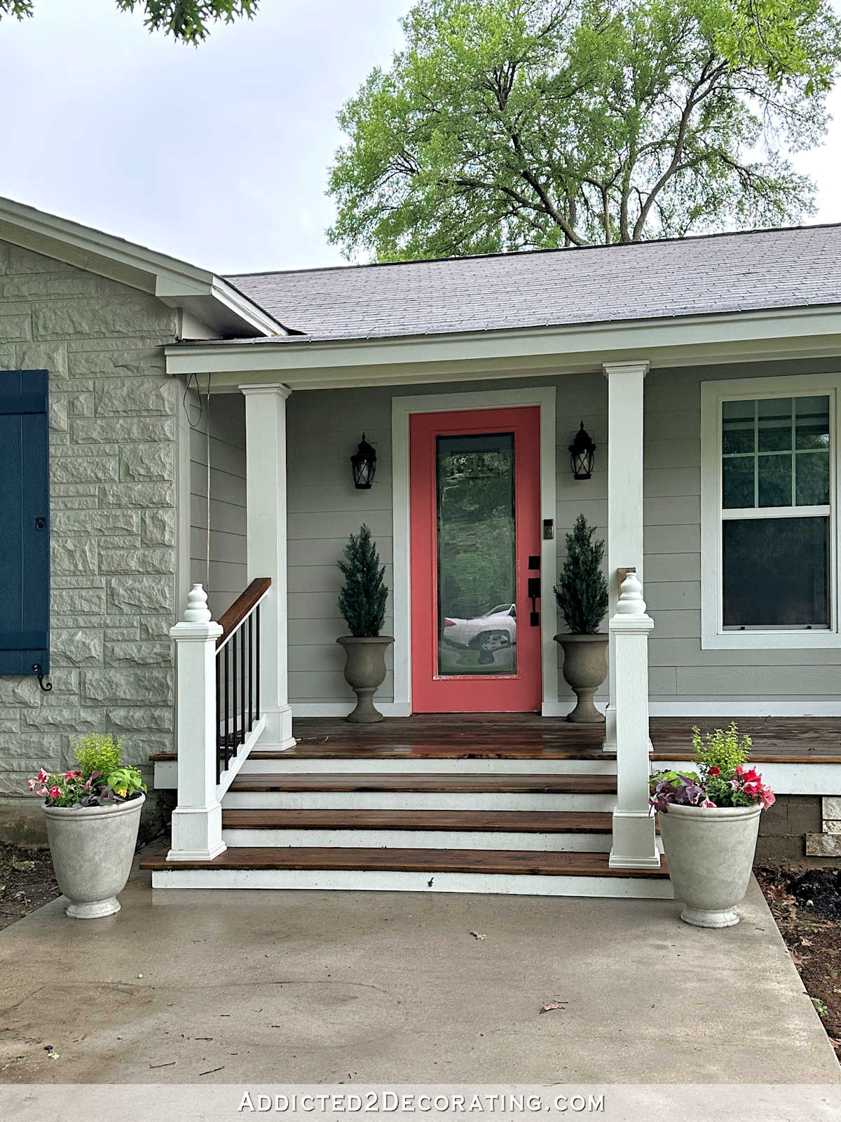 Front wood porch with colorful flowers and pink front door