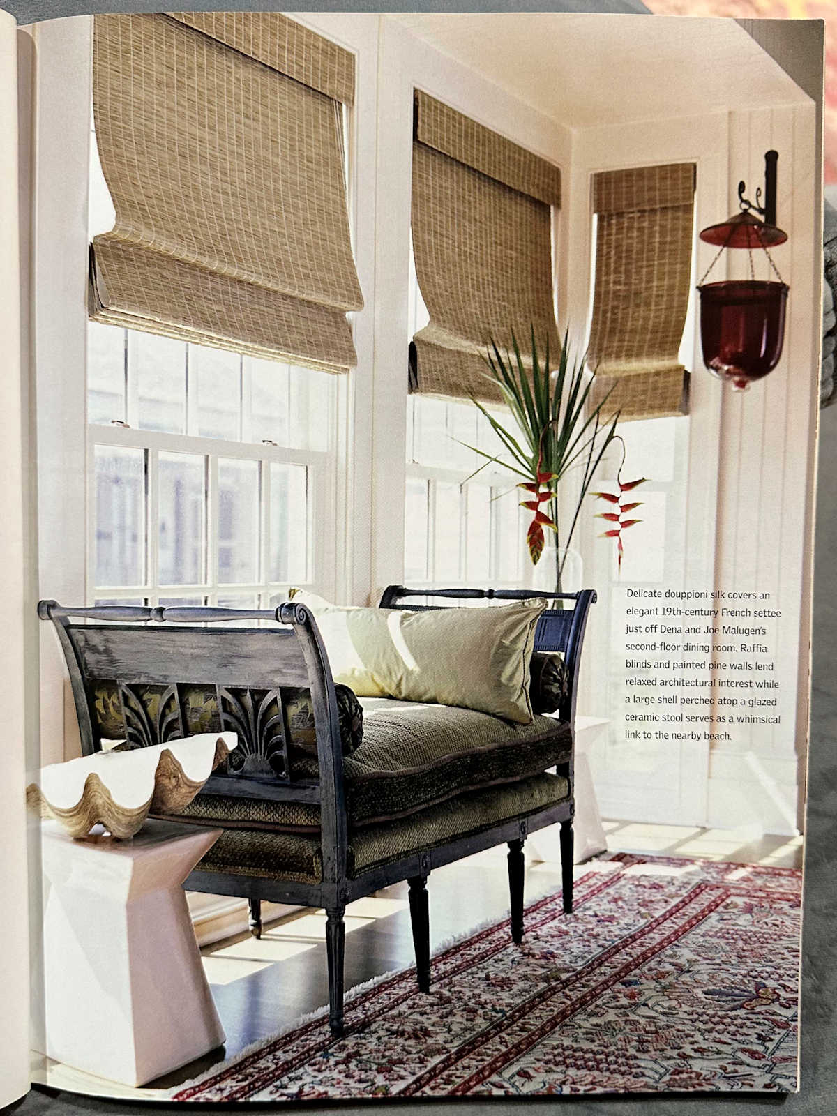 A sitting area with area rug, upholstered bench, and woven shades from 2006, still looks pretty in 2023