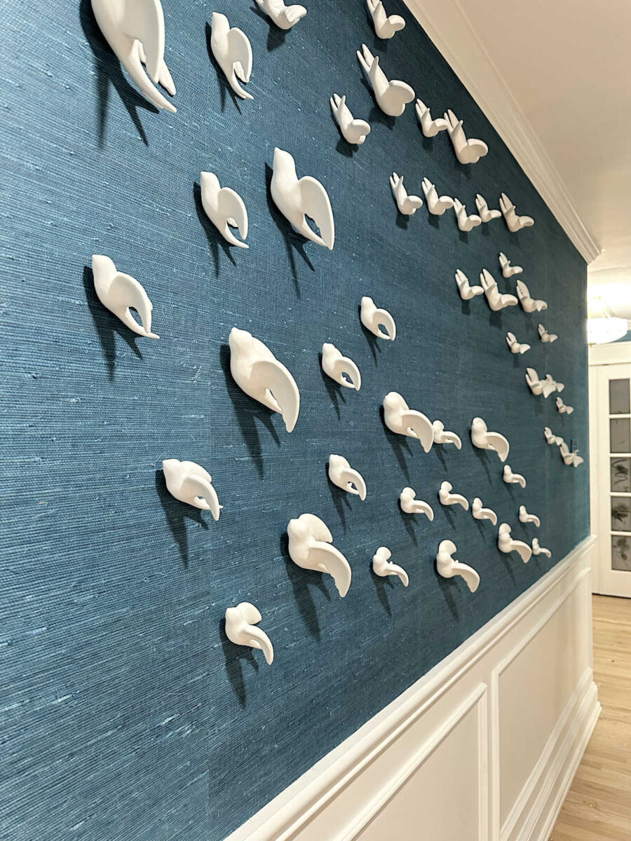 oiseaux en céramique accrochés selon un motif organique comme installation artistique sur le mur de la chambre