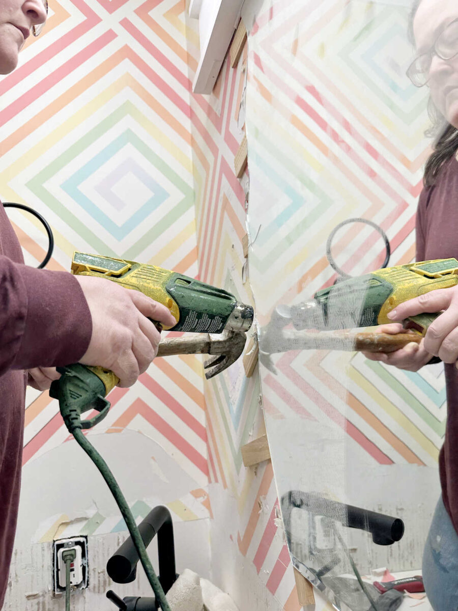 Using a heat gun and shims to remove a bathroom mirror that is glued to the wall