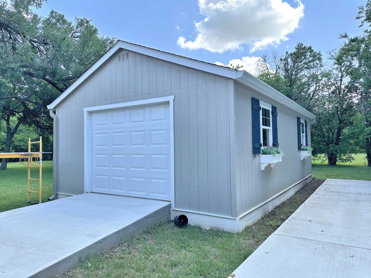 Back yard workshop, gray with white trim, dark blue shutters, window flower boxes